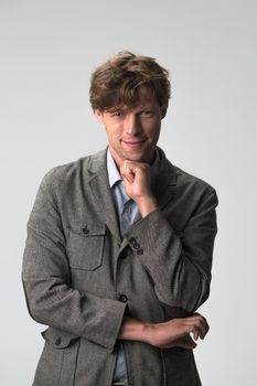 Hipster man in a suit with his leaned chin on a fist. Handsome confident caucasian standing with crossed arms isolated on white background. Half-length portrait.