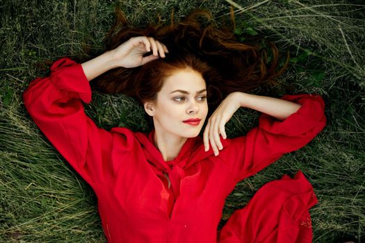 woman in red dress lies on the grass top view freedom. High quality photo