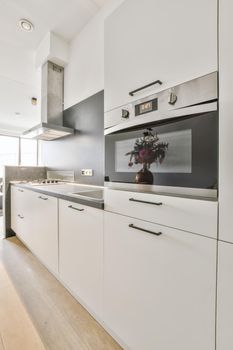 Interior of contemporary kitchen with stylish black cupboards and appliances near dining area in contemporary apartment