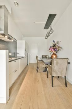 Interior of contemporary kitchen with stylish black cupboards and appliances near dining area in contemporary apartment