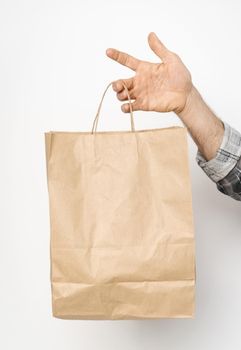 Paper bag for takeaway food. Delivery carrying. Man hand in plaid shirt twisted sleeve hand holding brown paper bag isolated on white background. Delivery concept.