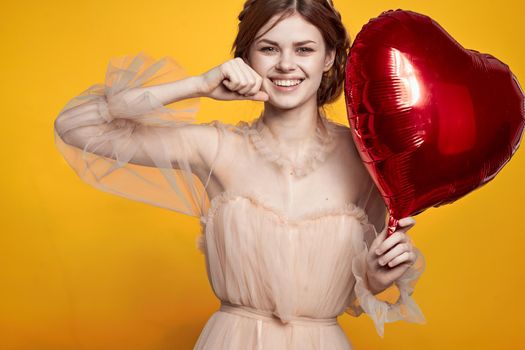 portrait of a woman Birthday party gift heart balloon yellow background. High quality photo