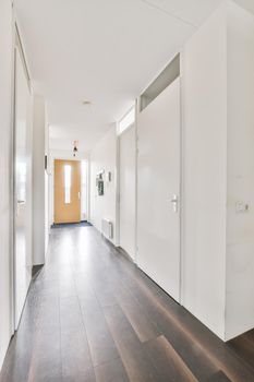 Attractive long hallway with white walls and dark parquet floors