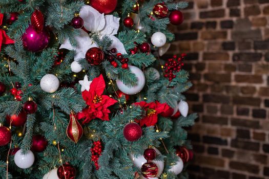 Closeup photo of red Christmas ball on fir tree next to fireplace