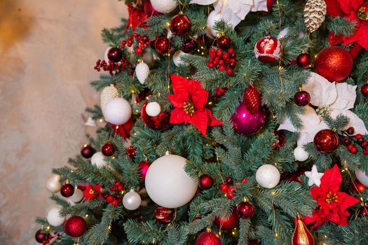 Closeup photo of red Christmas ball on fir tree next to fireplace