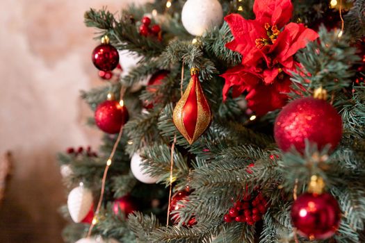 Closeup photo of red Christmas ball on fir tree next to fireplace