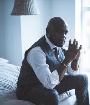 Serious Businessman is Pondering Strategies for Promoting his Business. A Good Deal. Man in a Formal Suit with Folded Hands Sits on his Bed. Close-up Portrait. High quality photo