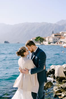 Bride and groom hug, standing off the coast of Perast. High quality photo