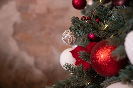 Closeup photo of red Christmas ball on fir tree next to fireplace