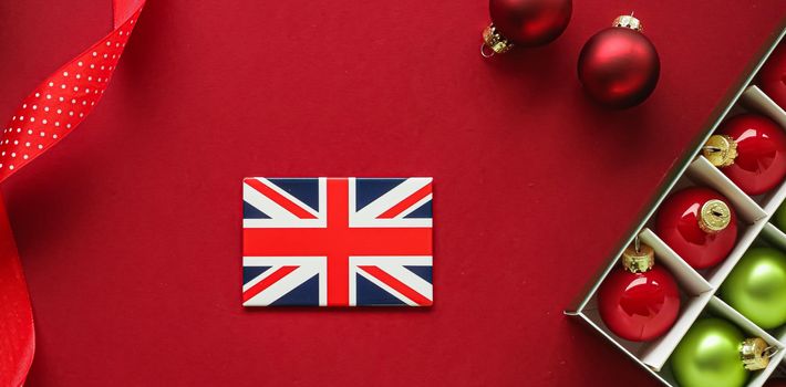 British Christmas tradition and holiday design concept. Union Jack flag of Great Britain and xmas ornaments and decoration on red background as flatlay top view.