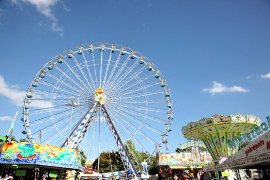 A beautiful ferris wheel on a holiday surrounded by rides- Photo