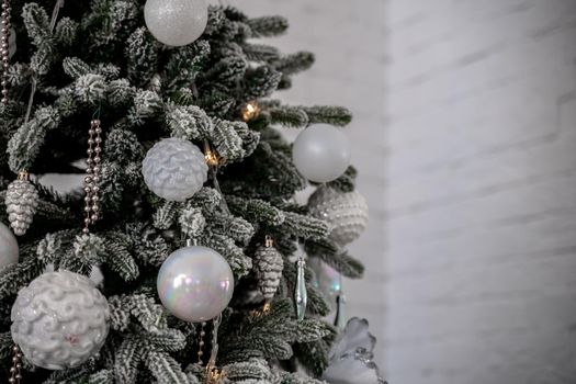 Close-up of a festively decorated outdoor Christmas tree with balls on a blurred sparkling fairy background. Defocused garland lights, bokeh effect