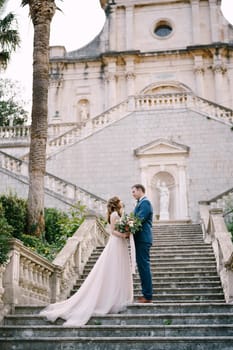 Bride and groom stand on the stone steps of the church in Prcanj. Montenegro. High quality photo