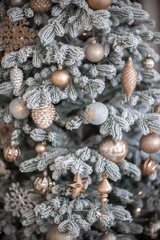 Close-up of a festively decorated outdoor Christmas tree with balls on a blurred sparkling fairy background. Defocused garland lights, bokeh effect