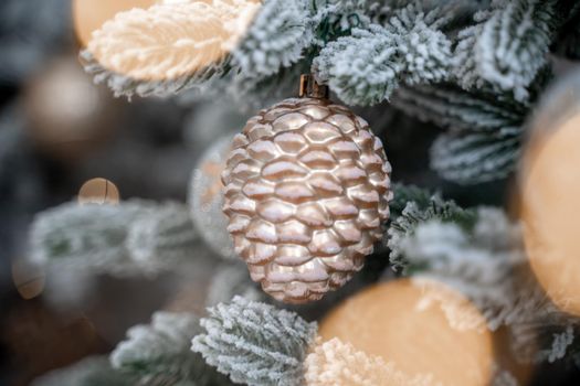 Close-up of a festively decorated outdoor Christmas tree with balls on a blurred sparkling fairy background. Defocused garland lights, bokeh effect