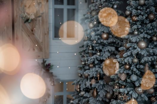 Close-up of a festively decorated outdoor Christmas tree with balls on a blurred sparkling fairy background. Defocused garland lights, bokeh effect