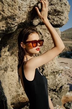 woman in black swimsuit sunglasses rocks posing summer luxury. High quality photo