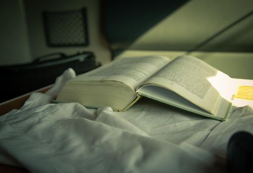 The open book lies on the table in the train compartment. A ray of light falls on the pages of a book