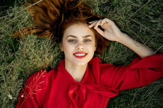 pretty woman in red dress lies on the grass landscape freedom. High quality photo