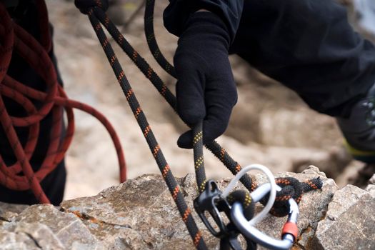 A young man in a helmet and with climbing equipment descends from the top of the mountain on a rope, the climber rappels with aperture-style self-braking belay in the snowy mountains.