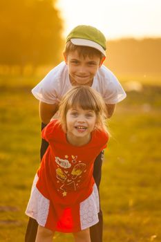 Children play an airplane and laugh against the backdrop of the setting sun. High quality photo