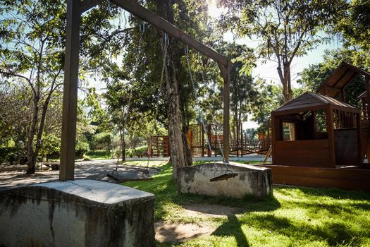 Empty swing is swinging in the playground. Playground on yard in the park.