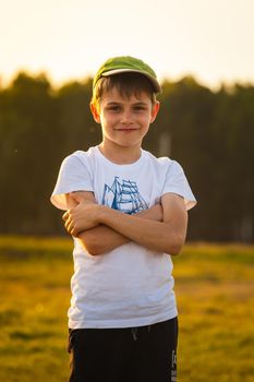 Boy smiling on the background of the forest at sunset. High quality photo