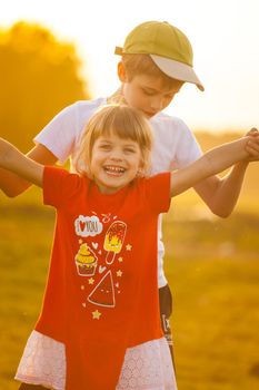 Children play an airplane and laugh against the backdrop of the setting sun. High quality photo