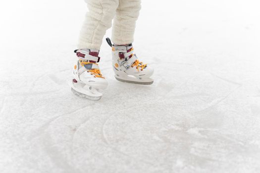 child is skating on the rink, legs close-up and place for text
