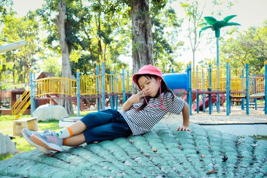 Smiling little girl poses for a photo in the playground on a warm summer day. Family spends time together on vacation.