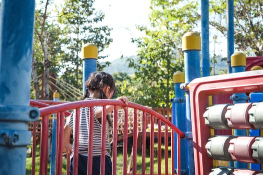 Active little girl running in the outdoor playground in the park. Happy child girl having fun on children playground. Play is learning in childhood.