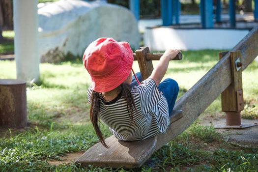 Active little girl playing on a seesaw in the outdoor playground. Happy child girl smiling and laughing on children playground. Play is learning in childhood.