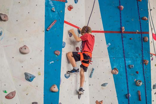 Boy at the climbing wall without a helmet, danger at the climbing wall.