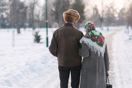 Back view of elderly couple walking in the park. Happy old people toghether though the years.