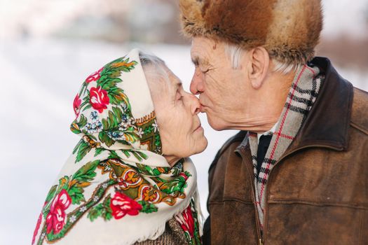 Portrait of happy senior couple. Elderly woman kiss her husband in weighty. old couple walking in the park in winter time. Happy family. Gold wedding.