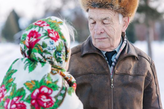 Senior people sitting on the bench in the park. Happy elderly couple spend time outside in winter.