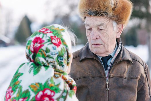 Senior people sitting on the bench in the park. Happy elderly couple spend time outside in winter.