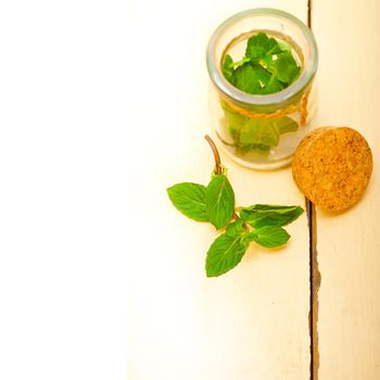 fresh mint leaves on a glass jarover a rustic white wood table