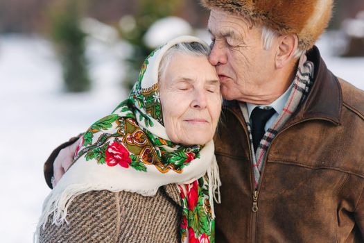 Portrait of senior couple. Elderly man kiss his wife in weighty. old couple walking in the park in winter time. Happy family. Gold wedding.