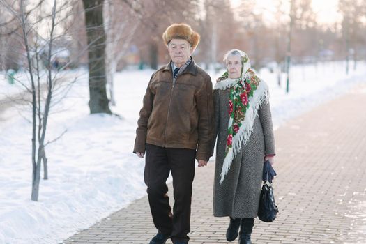 Romantic senior couple walking in the park in winter time. Love forever. background of white winter snow.