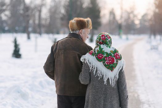 Back view of elderly couple walking in the park. Happy old people toghether though the years.