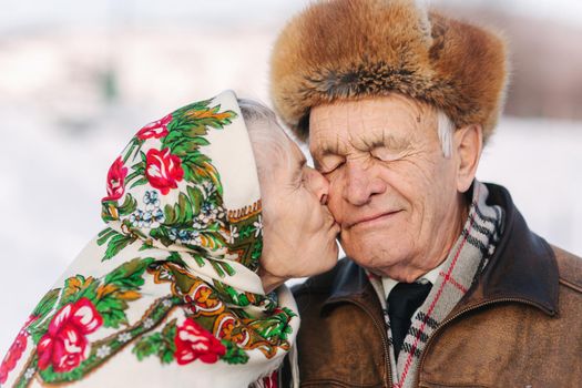 Portrait of happy senior couple. Elderly woman kiss her husband in weighty. old couple walking in the park in winter time. Happy family. Gold wedding.