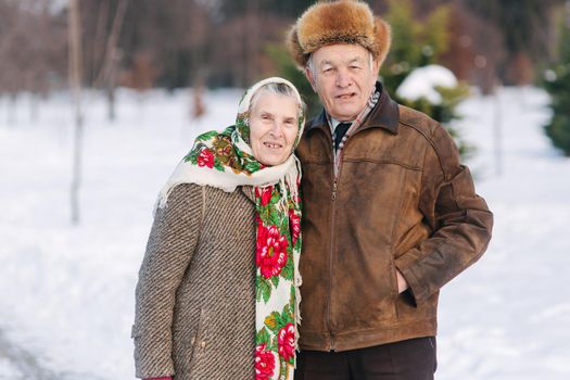 Elderly couple relaxing in winter time in the park. Happy grandfather and grandmother walking together.