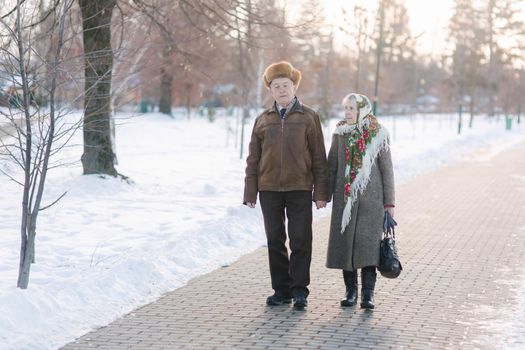 Romantic senior couple walking in the park in winter time. Love forever. background of white winter snow.