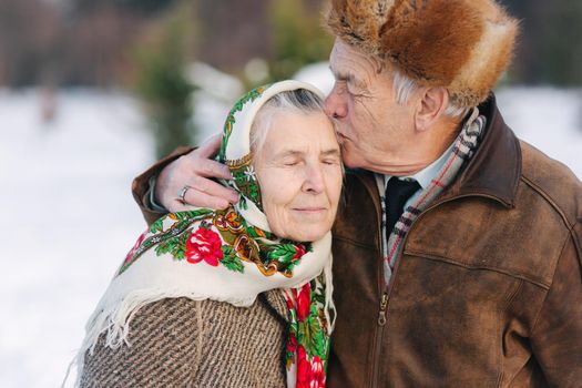 Portrait of senior couple. Elderly man kiss his wife in weighty. old couple walking in the park in winter time. Happy family. Gold wedding.