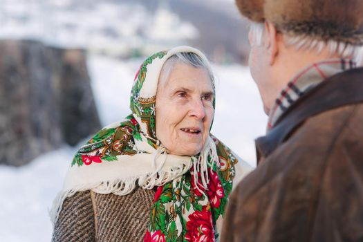 Senior people sitting on the bench in the park. Happy elderly couple spend time outside in winter.