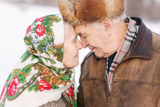 Portrait of happy senior couple. Elderly woman kiss her husband in weighty. old couple walking in the park in winter time. Happy family. Gold wedding.