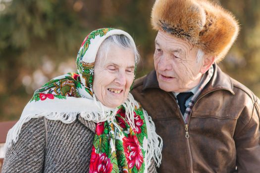 Senior people sitting on the bench in the park. Happy elderly couple spend time outside in winter.