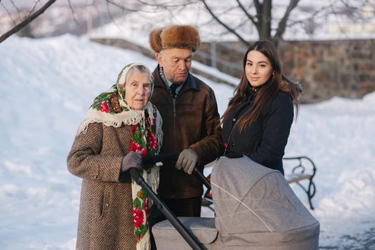 Grand Grandparents walking with a baby in beautiful pram. Winter time.