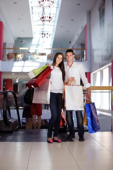 happy young couple with bags in shopping centre mall